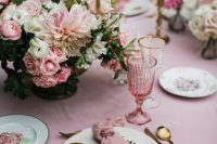 a chic secret garden wedding tablescape in rose, with beautiful and lush floral centerpieces, floral plates and pink glasses and linens