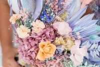 a colorful wedding bouquet with pink hydrangeas, peachy and pink roses, lilac fronds, pink bunny tails and blue grasses looks out of this world