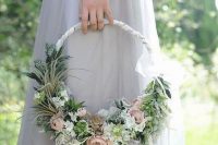 a dreamy hoop wedding bouquet of pale and pastel blooms, greenery, succulentsand a ribbon wrap on top is a chic idea