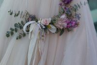 a dreamy hoop wedding bouquet with blush and purple blooms and eucalyptus and bows of long ribbons is a chic idea