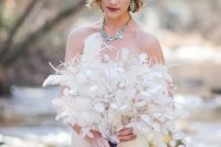 a dreamy lunaria and feather wedding bouquet with a vintage brooch and black ribbons is a lovely idea for a refined bridal look