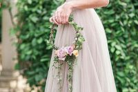 a fairy-tale hoop wedding bouquet with lots of greenery, peachy and pink roses is a very chic and cool idea for a fairy-tale wedding