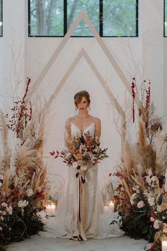 a fantastic boho fall wedding arch shaped as a house, with pampas grass, blush blooms, bold dried leaves is amazing