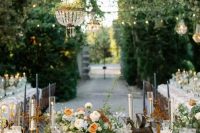 a fantastic secret garden wedding tablescape done in rust and peachy tones, with tall white and navy candles, refined blooms and chic linens