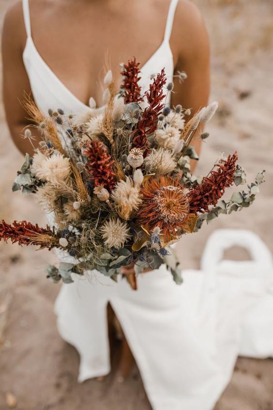 a gorgeous autumn wedding bouquet with plenty of texture, with thistles, allium, greenery, proteas and various blooms is a fantastic solution