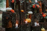 a gorgeous rustic fall wedding backdrop of tree stumps, pumpkins in various colors, bold blooms, thistles and eucalyptus is amazing