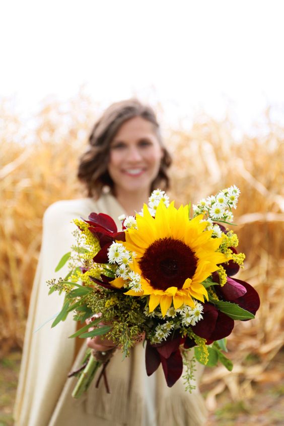 a lovely fall wedding bouquet with purple blooms and foliage, greenery, sunflowers and daises is a cool idea for a rustic or boho bride