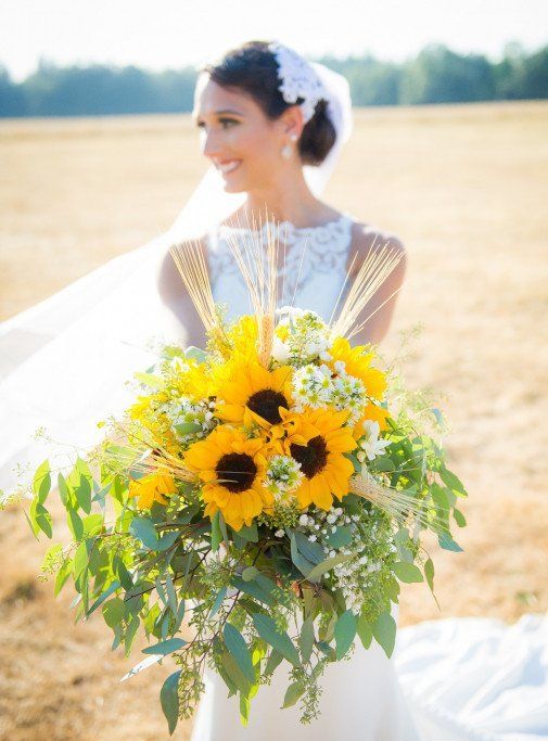 a lush rustic wedding bouquet of sunflowers, wheat, baby's breath and various types of greenery is a wow solution