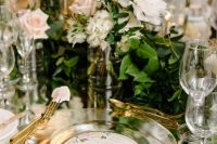 a luxurious secret garden wedding tablescape with a mirror tablescape, sheer plates, blush and white roses and greenery plus candles