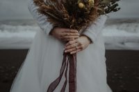 a moody fall or winter wedding bouquet of billy balls, eucalyptus, dried grasses and dried blooms plus long ribbons is a cool idea