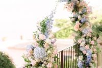 a simple floral wedding arch of blush, pink and blue blooms is a very pretty and delicate idea suitable for a garden wedding