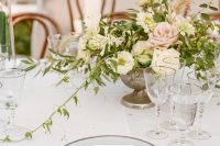 a sophisticated secret garden wedding tablescape with neutral linens, sheer plates, silver cutlery and a cool neutral and pink floral centerpiece