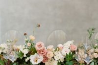 a stylish and chic garden wedding tablescape with a greenery and pink bloom runner, neutral linens and silver cutlery is wow