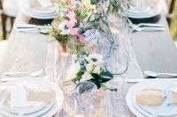 a subtle spring wedding tablescape with a neutral runner, pink, blue and white blooms, blue glasses is a great idea