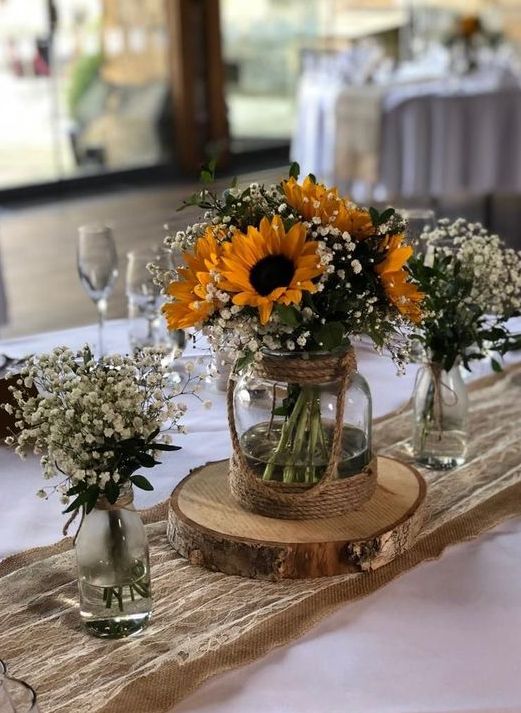 a triple rustic wedding centerpiece of vases with baby's breath and sunflowers is a gorgeous idea for a bright summer wedding in rustic style