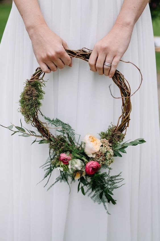 a woodland hoop wedding bouquet of vine, moss, greenery, peachy and pink blooms is a pretty idea for a woodland wedding