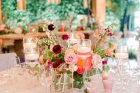 an elegant secret garden wedding table setting with bold blooms and greenery, floating candles, burgundy napkins and gold edge plates