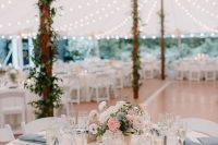 an elegant wedding tablescape with blue napkins, a pink, white and blue floral centerpiece and some glasses is a very chic idea