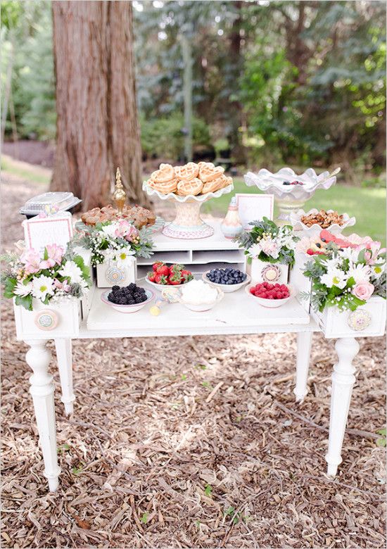 an elegant vintage waffle bar with a white vintage table, pink and white blooms, greenery, waffles, toppings and sauces