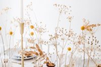 a beautiful and easy cluster wedding centerpiece of billy balls, dried leaves, grasses and candles in tall candlesticks is a pretty rustic idea