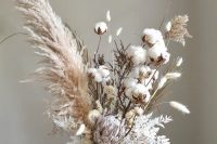 a beautiful and textural wedding centerpiece with cotton, pampas grass, whitewashed leaves, a king protea and bunny tails is amazing