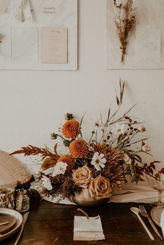 a beautiful boho fall wedding centerpiece of white, rust, neutral blooms, bold foliage, greenery is a very refined idea to rock