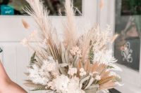 a beautiful dried flower wedding centerpiece of white and pink dried blooms, grasses, leaves and fronds, fern leaves is amazing