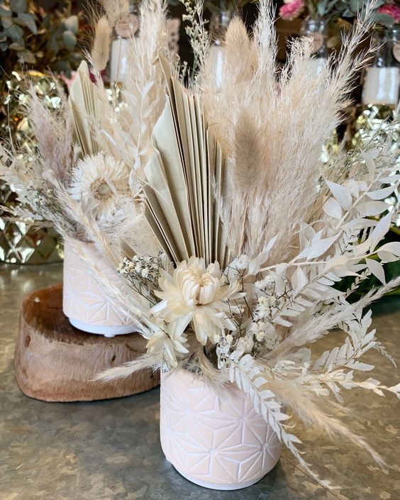 a beautiful wedding centerpiece of dried blooms, pampas grass, dried fronds and dried whitewashed leaves is a pretty idea for a boho wedding