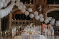 a beautiful wedding reception styled with white balloons, lights, pampas grass and neutral blooms is a very cool idea