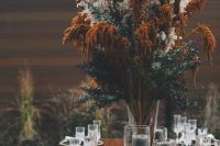 a bold and oversized fall boho wedding centerpiece of pampas grass, greenery and rust blooms, with grey candles around is an amazing idea