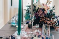 a bold iridescent and holographic wedding tablescape with a pink runner, navy napkins, turquoise candles and iridescent floral arrangements