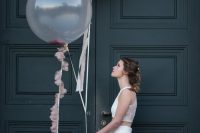 a bride carrying a blush with gold balloon and a clear one with pink tassels looks very cool and fresh