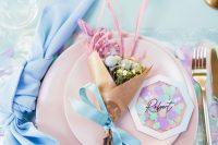 a bright and fun iridescent wedding place setting with blue linens, pink napkins, pink blooms and grasses and a cool card is wow