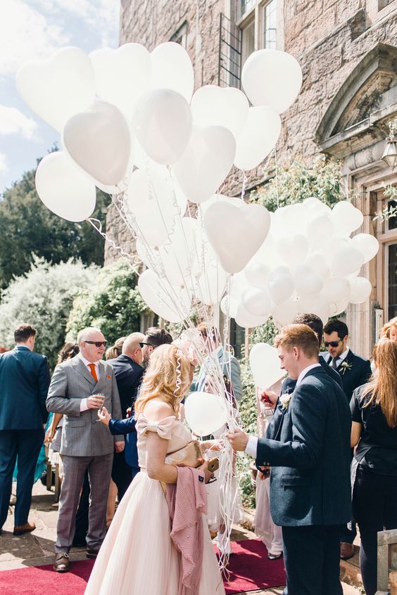 a bunch of white heart-shaped balloons instead of a traditional wedding bouquet is a very fun and bold idea to rock
