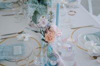 a chic iridescent wedding tablescape with turquoise and blush runners and napkins, blue candles and blue and blush florals is amazing