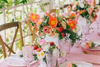 a colorful and cool bridal shower tablescape with a pink tablecloth, bold orange and pink blooms with strawberries, pink glasses is very cute