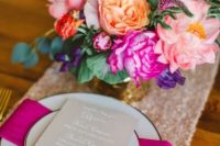 a cool and bold bridal shower place setting with a pink sequin runner, hot pink and light pink floral centerpiece, a fuchsia napkin and gold cutlery