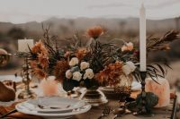 a fall boho wedding centerpiece of a gilded bowl, neutral and rust-colored blooms and greenery, candles is a lovely idea