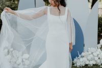 a gorgeous plain sheath wedding dress with thick straps, a square neckline and a long train and a pearl capelet for a modern lux look