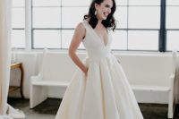 a gorgeous plain wedding ballgown with thick straps, a deep neckline and a pleated skirt with pockets and a train plus vintage statement earrings