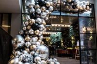 a jaw-dropping silver, gold and black balloon garland over the entrance to the wedding reception space is a gorgeous idea