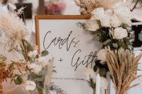 a lovely summer or fall boho wedding centerpiec eof white roses, pampas grass, wheat, candles and a neutral sign is a very cool idea for a boho space