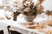 a lush and wild-looking wedding centerpiece fully made of dried blooms, grasses and twigs in a grey bowl is a beautiful idea for a non-traditional wedding