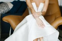 a modern strapless wedding ballgown with a geometric and deep neckline and a train, grey ankle strap shoes and statement accessories