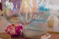 a pretty iridescent wedding place setting with a holographic escort card, a teapot, pink stones and an iridescent place setting