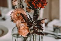 a simple and lovely fall boho wedding centerpiece of vases, blush and dried rust and deep purple blooms is a lovely solution to rock