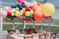 a super colorful wedding tablescape with bold candles and blooms, with an oversized colorful balloon installation over the table