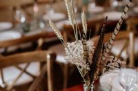a very easy boho wedding centerpiece of dried grasses and feathers is a lovely and relaxed idea for a boho wedding