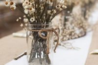 a very simple boho wedding centerpiece of dried daisies in a jar is a lovely and easy to DIY idea for a wildflower wedding