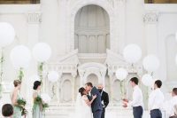 a wedding ceremony space with white balloons with greenery, white and pastel blooms is a very chic and cool and fresh idea